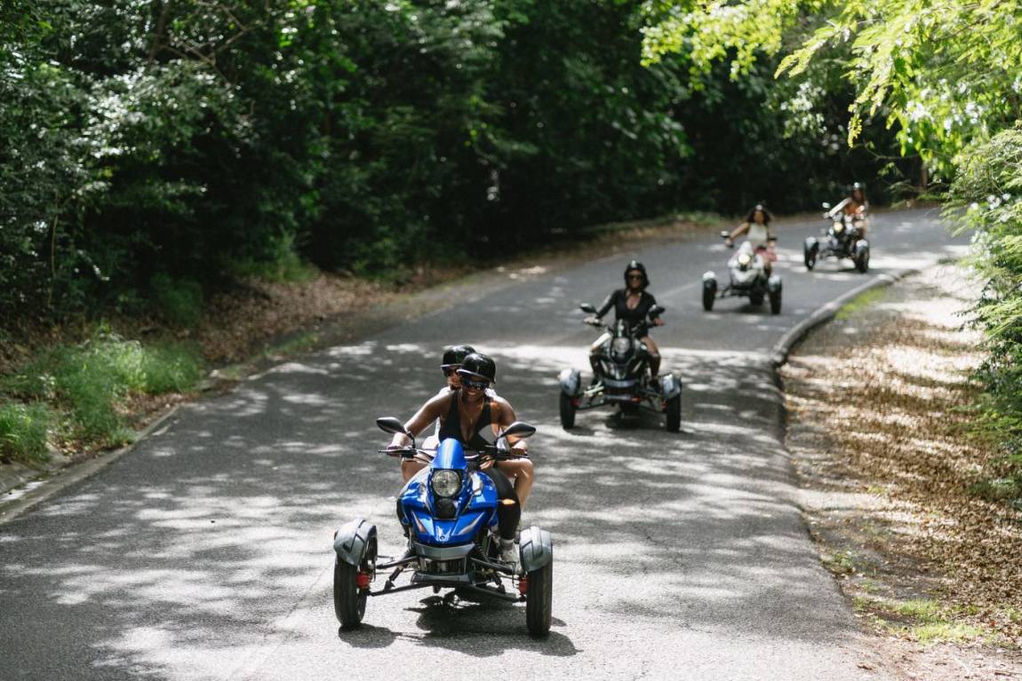 A group riding three-wheel trikes along a sunny forest road on St. John